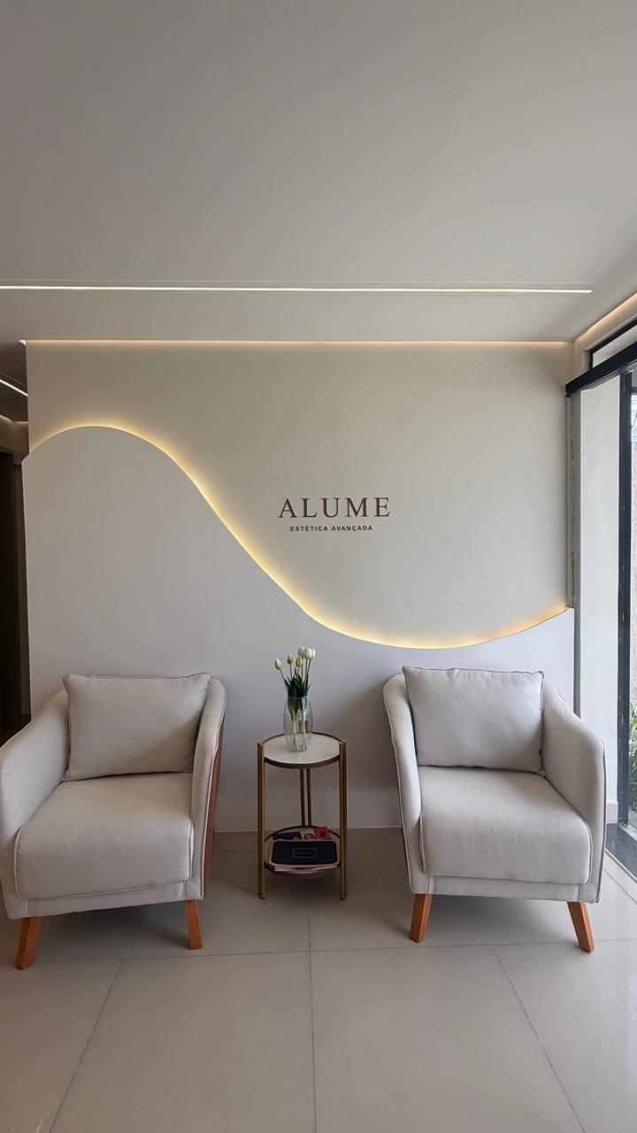 Sala de espera com poltronas e detalhe iluminado do logo